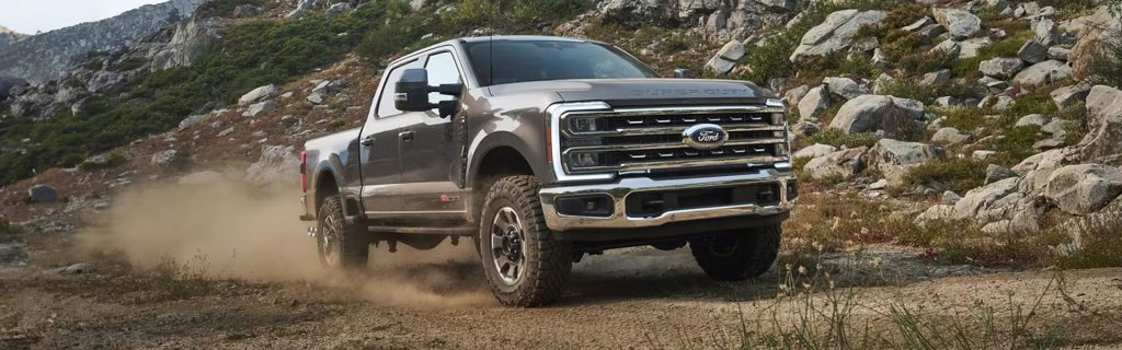 An all-new Gray 2024 Ford F-250 SD driving up a rock covered mountain side. - Jack Madden Ford Norwood, MA
